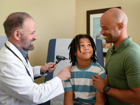 Provider checking boy's ear for infection