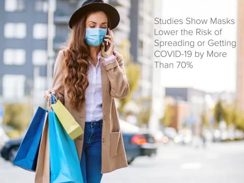 Woman walking outdoors while carrying shopping bags and talking on the phone.