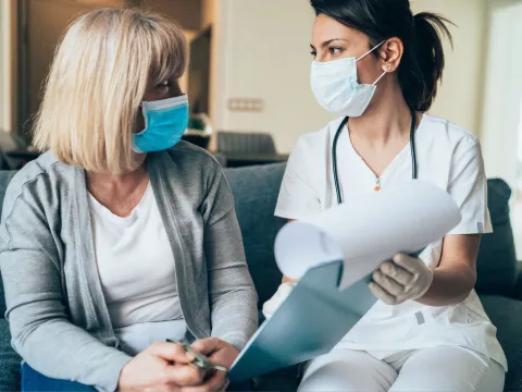 A Health Care Professional Goes Over Paperwork with a Patient in the Waiting Room.