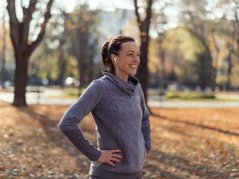 A Woman Smiles as She Takes a Break From a Jog in the Park