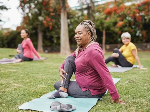 Three Senior Women Stretch in the Park Just Prior to Yoga