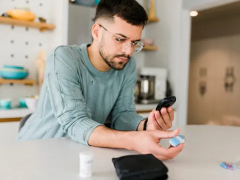 A Man Checks His Glucose Levels in His Kitchen