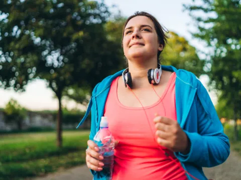 A Woman Jogging in a Park Carrying a Water Bottle