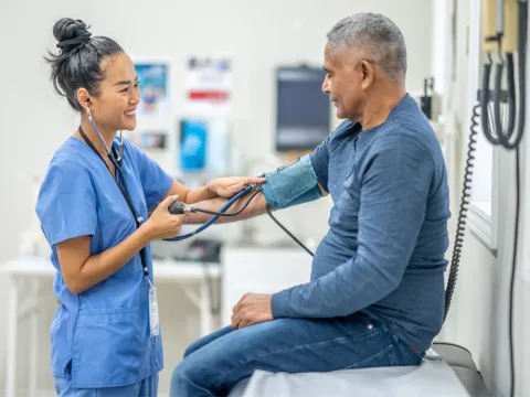 A Nurse Smiles as she Takes a Patient's Blood Pressure Readings.