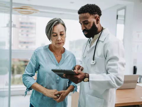 A Patient Looks Over Her Chart with a Provider on a Tablet in an Exam Room
