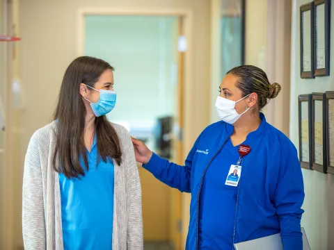 Nurse with her hand on patient in hallway at outpatient clinic