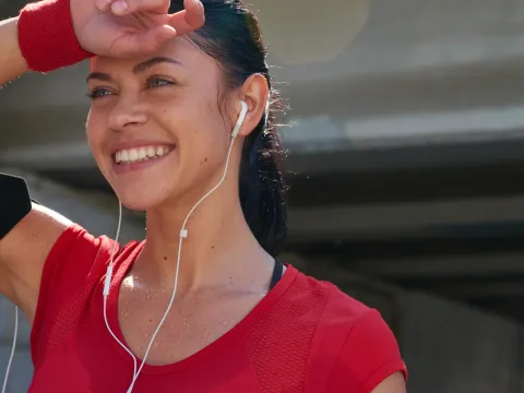 A woman with headphones in, dries off her forehead post workout.