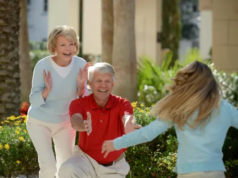 A girl sees her grandparents for the first time and runs to hug them.