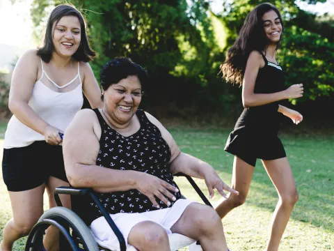 A woman in a wheelchair enjoys the outdoors with her daughters during the summer.