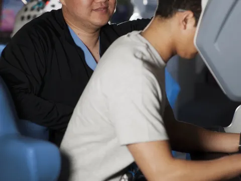 Two men looking at a robotic surgery control station.