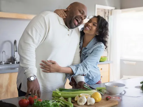 A couple hugging each other while cooking on the kitchen