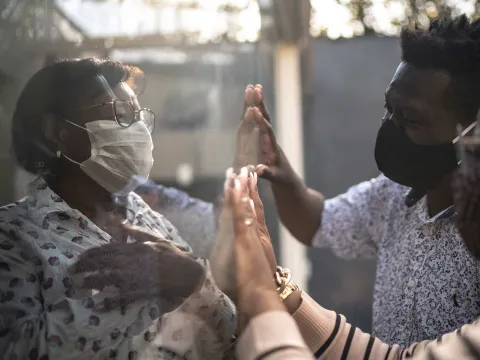 A family visiting a quarantined loved one through a window.