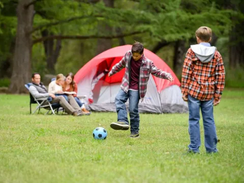 Two boys play soccer on a family camping trip