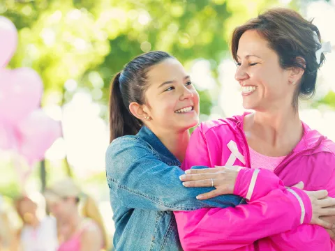 A daughter hugs her mother as they participate in a breast cancer walk.