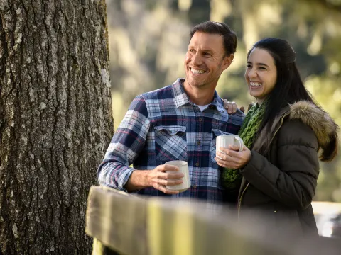 A couple holding mugs while outdoors in the winter.