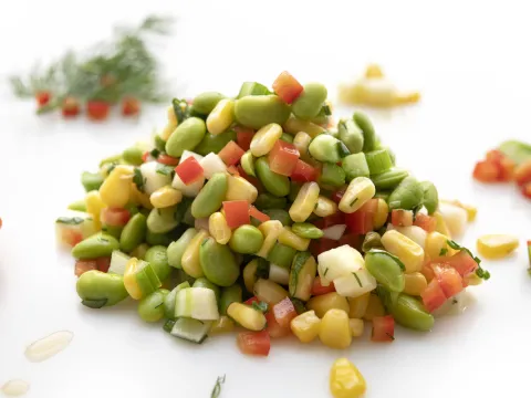 Mound of edamame corn salad on white surface