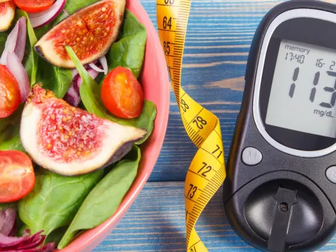 A picture of a salad, measuring tape, and a sugar monitor