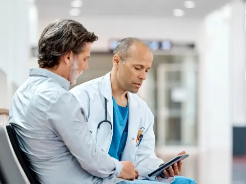 A physician and his male patient read documents together.