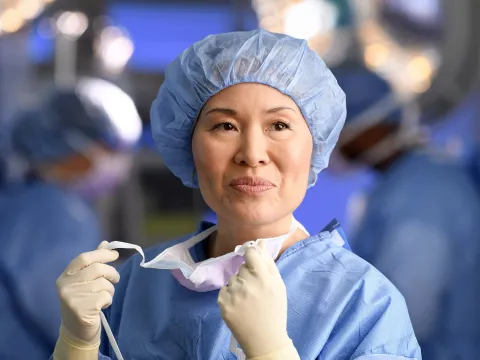 Smiling female surgeon taking off her mask