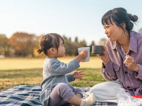 A Mother and Daughter Sit at a Picnic Enjoying Tea
