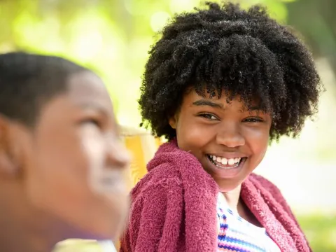 A girl smiles at her older brother