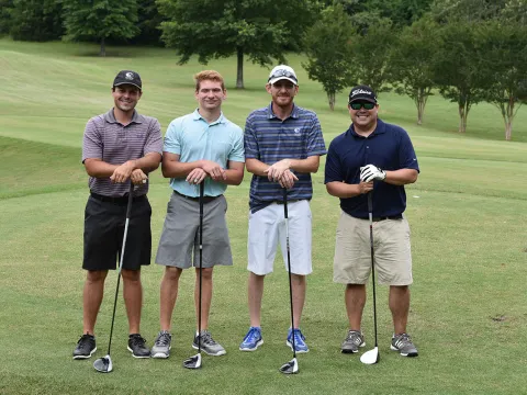 Group of golfers standing with golf clubs in hand.