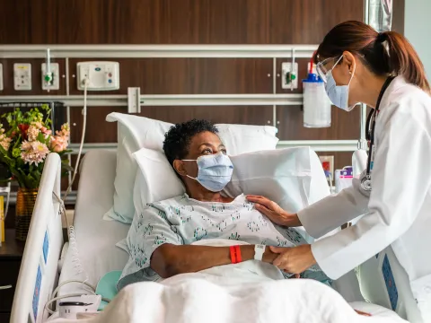 A physician comforting a patient of color