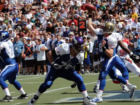 Football star, Drew Brees, passing the ball to a player.