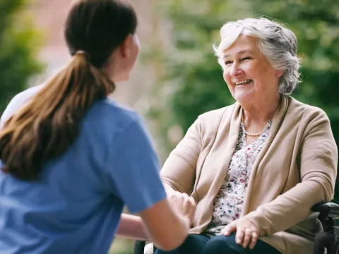 An elderly woman talks and laughs with her caretaker
