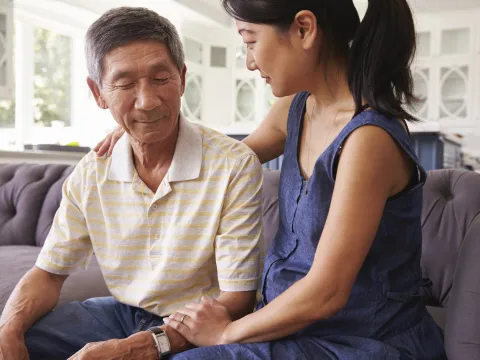 A father and adult daughter comfort one another.