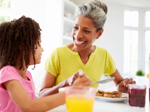 A grandmother and granddaughter eating breakfast together.