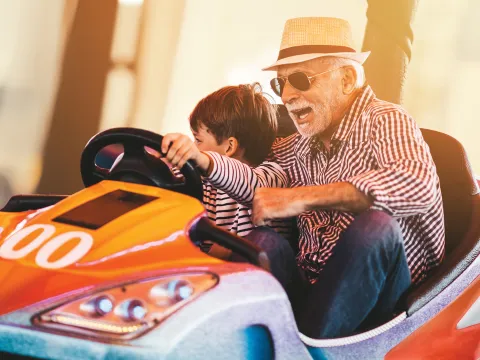 Grandfather and grandson playing in a bumper car