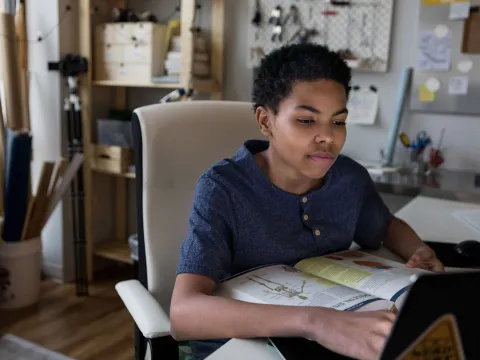 A young boy does his homework at the kitchen table
