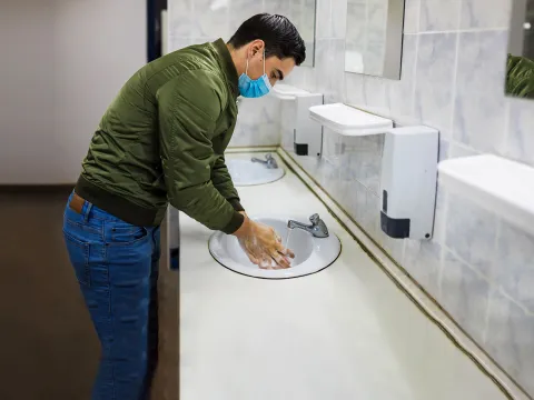 A man washing his hands in a public restroom.