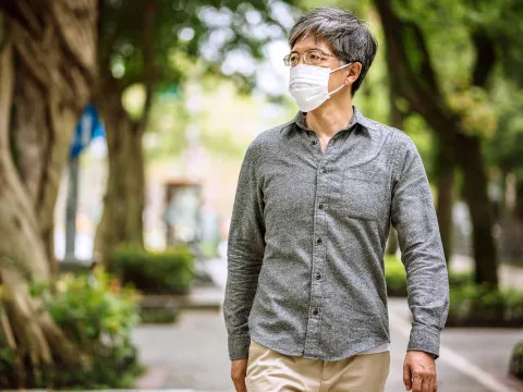 A man wearing a mask while walking outside.