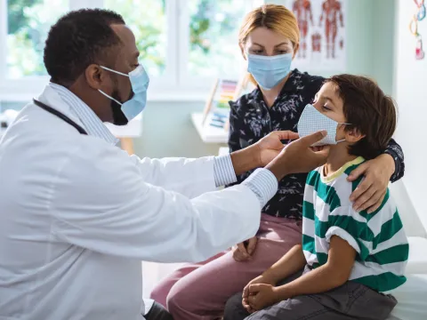 A doctor examines a boy during an appointment.