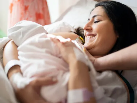 A new mom holds her infant after delivery.