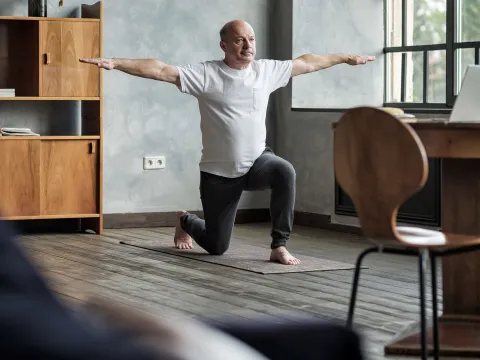 A older man stretching at home.