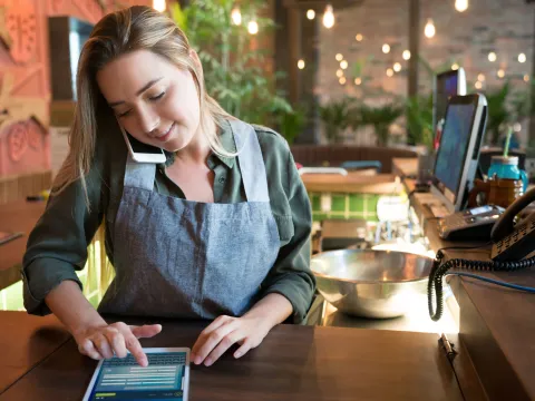 A young waitress taking a to-go order over the phone.
