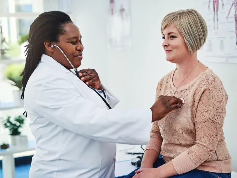 A patient having her heart listened to.