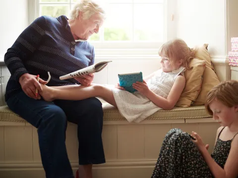 A woman doing a crossword with her grandchildren.