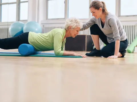 A woman uses a foam roller on her hip flexors.