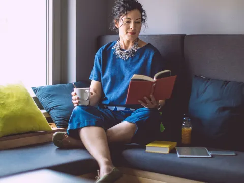 A woman reading a book at home.