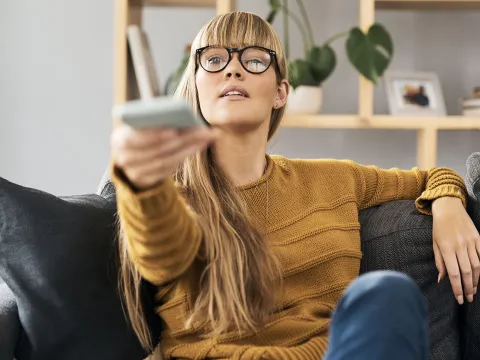 Woman at home turning on her tv.