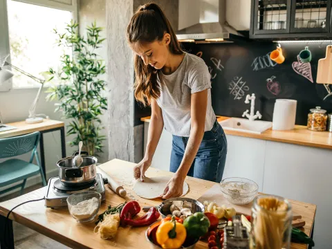 A young woman cooking in her kitchen.