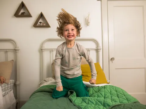 Little boy jumping on the bed.