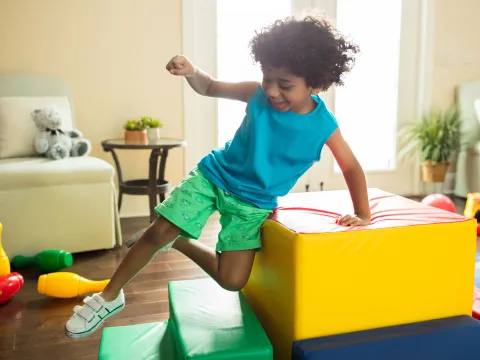 A little boy jumping in the family room.