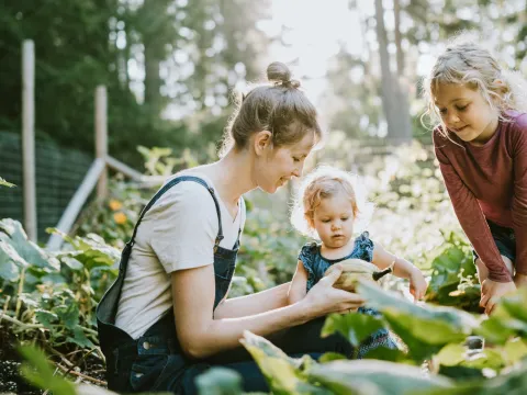 A young woman with two children in the garden.