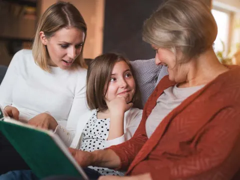 Grandmother mother and girl reading on couch