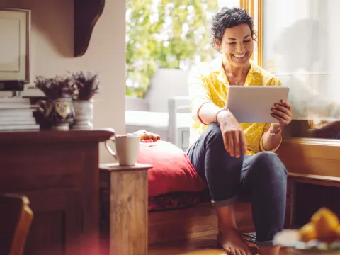 Middle-aged woman smiling at home with tablet